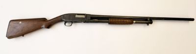 un vieux fusil posé sur une surface blanche, muni d'une crosse en bois
