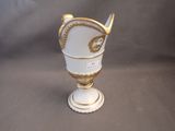 a white vase with a gold decoration on it