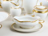a lot of white and gold dishes and cups on the table