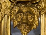 a gold clock with a face of a lion on it