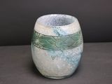 a white vase with green designs on it on a table