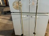 pair of brass floor lamps with glass bulbs on each of them