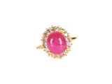 un gros plan d'une bague en pierre rose sur fond blanc