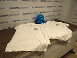 une pile de t-shirts blancs posés sur une table devant un mur