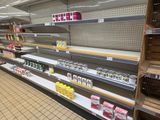 many empty shelves in a grocery store with drinks on them