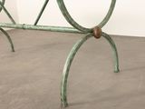 a green metal bench with a wooden seat on a cement floor