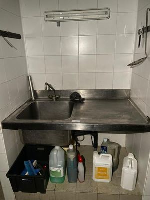 un lavabo dans un coin de la salle de bains, avec de nombreux produits d'entretien