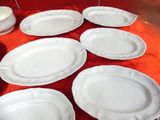 many white plates on a table with a red table cloth
