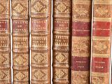 several old books are lined up in a row on a shelf
