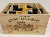des bouteilles de vin dans une caisse en bois posée sur une surface blanche