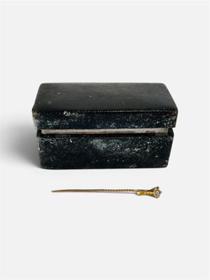 une boîte noire munie d'une poignée dorée, posée sur une surface blanche