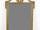 un miroir orné d'un cadre doré, surmonté d'un oiseau