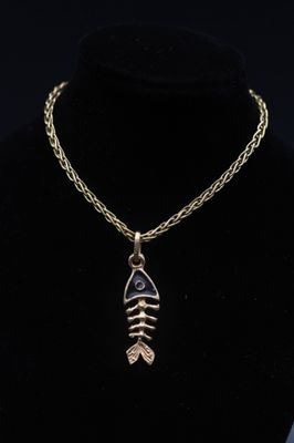 un collier en or avec un pendentif en forme d'arête de poisson sur un mannequin noir