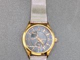an image of a silver and gold wrist watch on a gray surface
