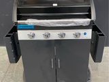a black grill with two burners on a pallet next to a black wall