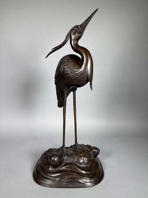 an image of a bronze statue of a crane standing on a rock