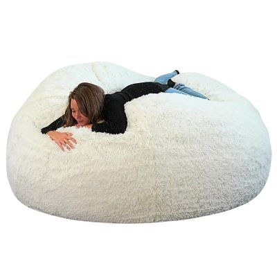 une femme allongée sur un pouf blanc, sur fond blanc