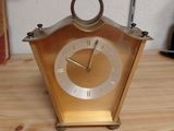 a gold clock sitting on top of a wooden table