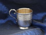 a silver cup with a handle on a blue cloth