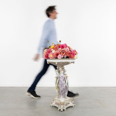 un homme passant devant un vase orné de fleurs