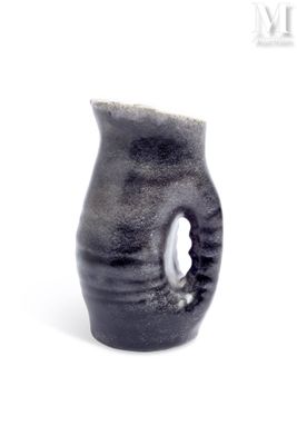 a black vase with a hole in it on a white surface