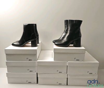 deux paires de bottines en cuir noir posées sur des cartons