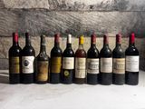 several bottles of wine are lined up on a table in front of a brick wall