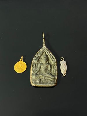 a close up of a gold pendant and a silver pendant on a black surface