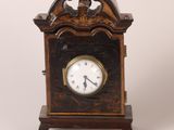 une petite horloge en bois surmontée d'un oiseau