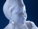 a white sculpture of a woman with a hat on