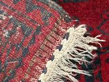 a close up of a red and black rug with a fringe