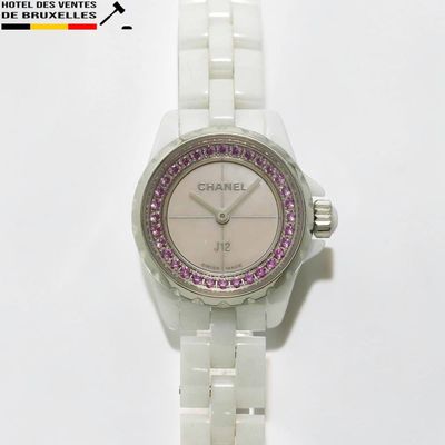 une montre blanche ornée de cristaux violets, posée sur un fond blanc