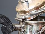 a silver tea pot with a handle on a table