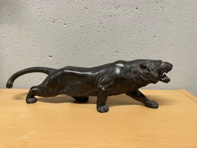 une statue noire représentant un lion posée sur une table en bois