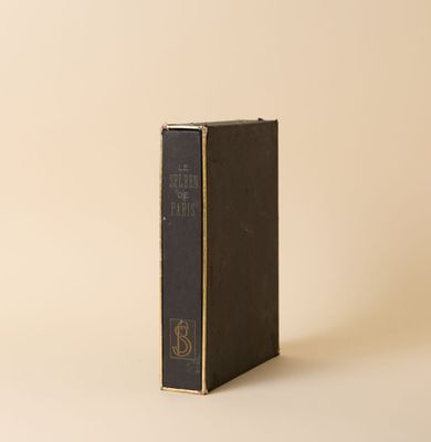 un vieux livre posé sur une table à côté d'un mur blanc