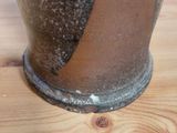 a brown vase sitting on top of a wooden table