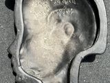 a metal mold with a face on it on the ground