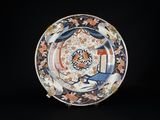 une image représentant une assiette bleue et orange sur laquelle figure un oiseau