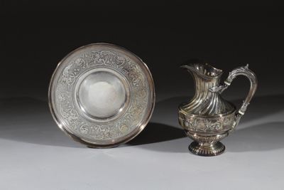 une paire de vases en métal argenté et un bol en métal argenté posés sur un support blanc