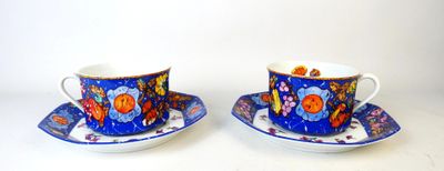 two cups and saucers sitting on a white table