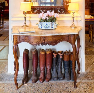 une table sur laquelle sont posées plusieurs paires de bottes, devant un miroir