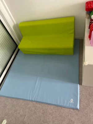 un coussin vert et bleu posé par terre près d'une fenêtre