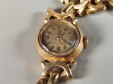 a gold watch with a chain around it on a white surface