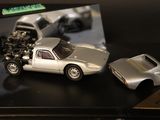 a silver toy car and a silver model car on a table