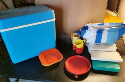 une table sur laquelle sont posés une glacière, des assiettes et des tasses