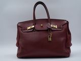 a red leather handbag with gold hardware on the handles