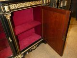a black and gold cabinet with a red velvet seat