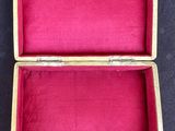 an open wooden box with pink velvet lining on a blue surface