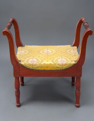 une image représentant un banc en bois dont l'assise est recouverte d'un tissu jaune et rouge