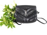 a small black purse with a chain strap next to a plant